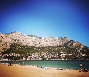 People at beach against blue sky