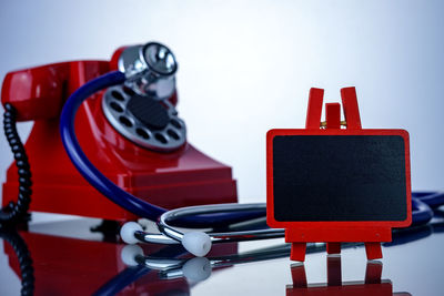 Close-up of blackboard by stethoscope and rotary phone on table