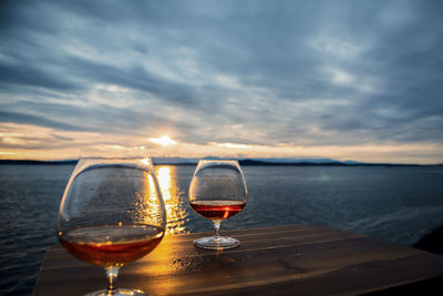 Cognac glasses on seaside deck table at sunset.