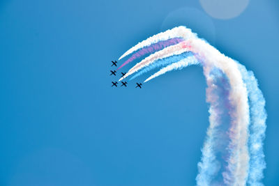 Low angle view of jets flying against blue sky