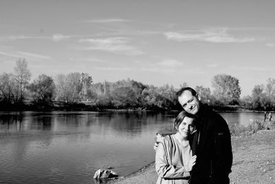 Portrait of couple standing with arm around by lake