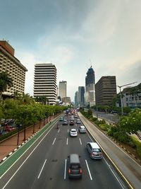 Traffic on road amidst buildings in city against sky