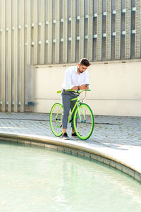 Outdoor portrait of handsome young man with mobile phone and fixed gear bicycle in the street.