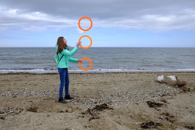 Rear view of lady juggling at beach 