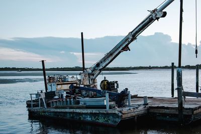 Fishing boat on pier over sea against sky