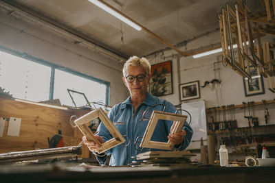 Low angle view of senior craftswoman examining frames at workshop