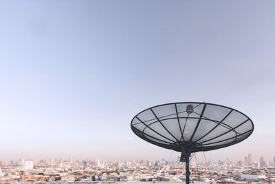 Ferris wheel by modern buildings against clear sky