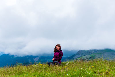 A young female hiker on a break during a hike on a cloudy summer day in the french alps