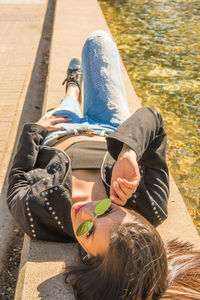 High angle view of young woman wearing sunglasses lying on retaining wall