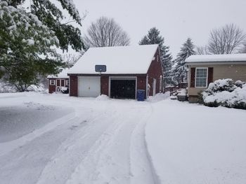 Snow covered houses by building during winter