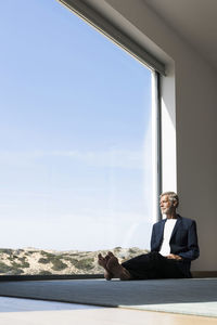 Senior businessman sitting at panorama window looking out