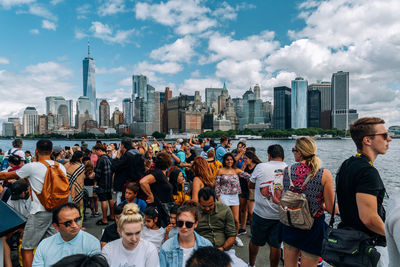 People at modern buildings in city against sky