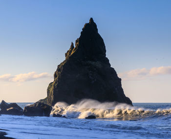Rock formation on beach against sky