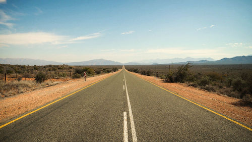 Road amidst field against sky