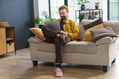 Side view of woman sitting on sofa at home