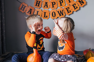 A little blonde girl and a boy in a pumpkin costume for halloween, trick or treat