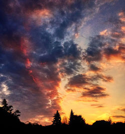 Low angle view of silhouette trees against dramatic sky