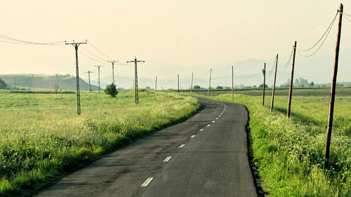 Road amidst field against clear sky