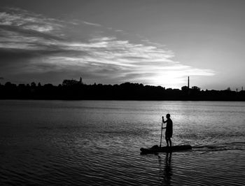 Silhouette man standing in lake against sky