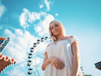 Portrait of smiling young woman in amusement park against sky