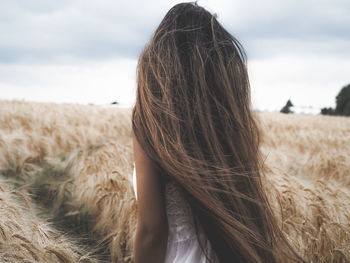 Rear view of woman standing on field against sky