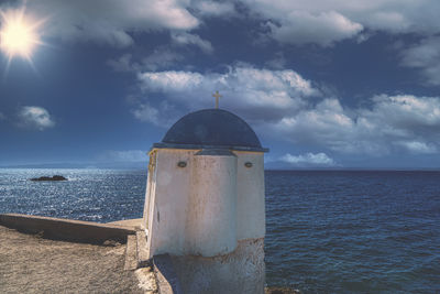 Lighthouse by sea against sky