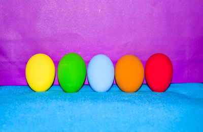 Close-up of easter eggs on blue table against purple wall