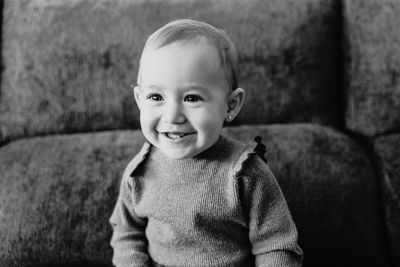 Smiling baby girl looking away while sitting on sofa