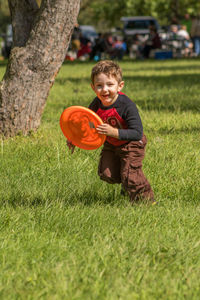 Portrait of boy playing with plastic disc on grassy field at park