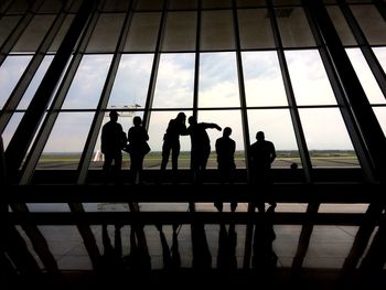 Silhouette people against sky seen through glass window