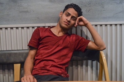 Portrait of young man looking away while sitting on railing