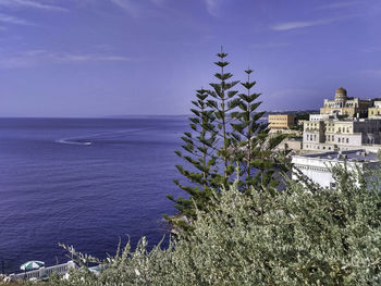 Scenic view of sea by buildings against sky