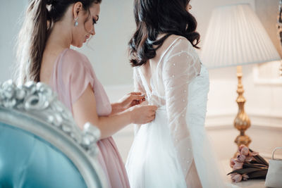 Midsection of mother and daughter standing on bed