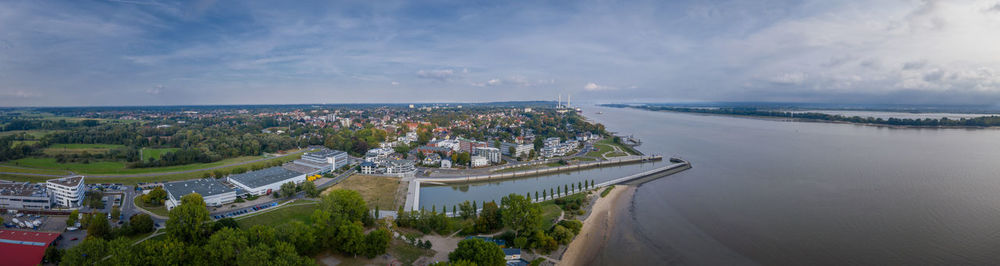 High angle view of city by sea against sky