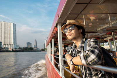 Tourist wearing hat standing in boat on river