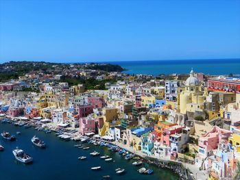 High angle view of city by sea against clear blue sky