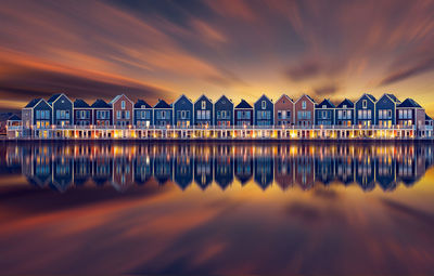 Symmetry view of buildings by sea against sky