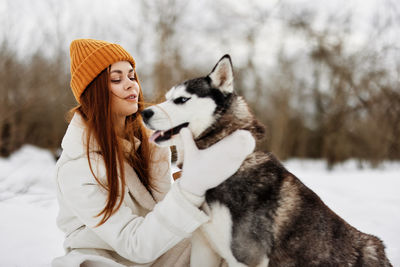 Portrait of woman with dogs on snow covered field