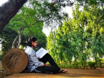 Man sitting on book against trees