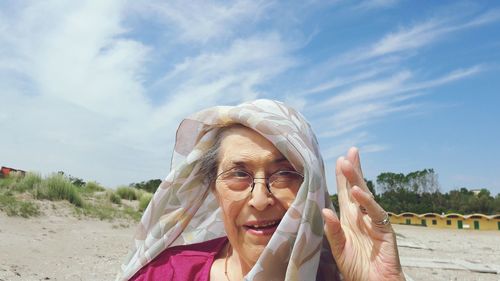 Portrait of senior woman wearing headscarf against sky