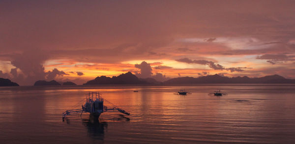 People in boat on sea against sky during sunset