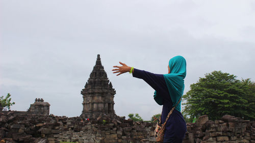 Low angle view of woman standing on rock against sky