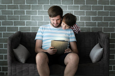 Young couple sitting against wall