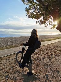Woman sitting on exercise equipment at beach 