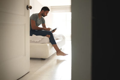 Full length of man using mobile phone at home