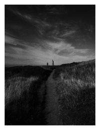 View of field against cloudy sky