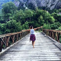 Rear view of woman walking on footbridge