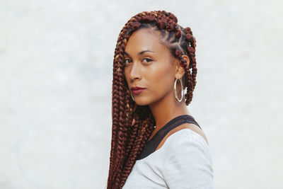 Portrait of young woman with braided hair against white background