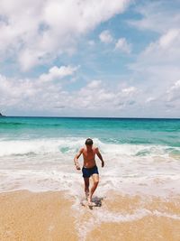 Full length rear view of shirtless man on beach