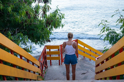 Rear view of woman standing by lake